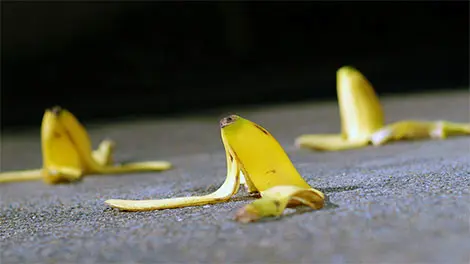 Three bananas on an asphalt ground.